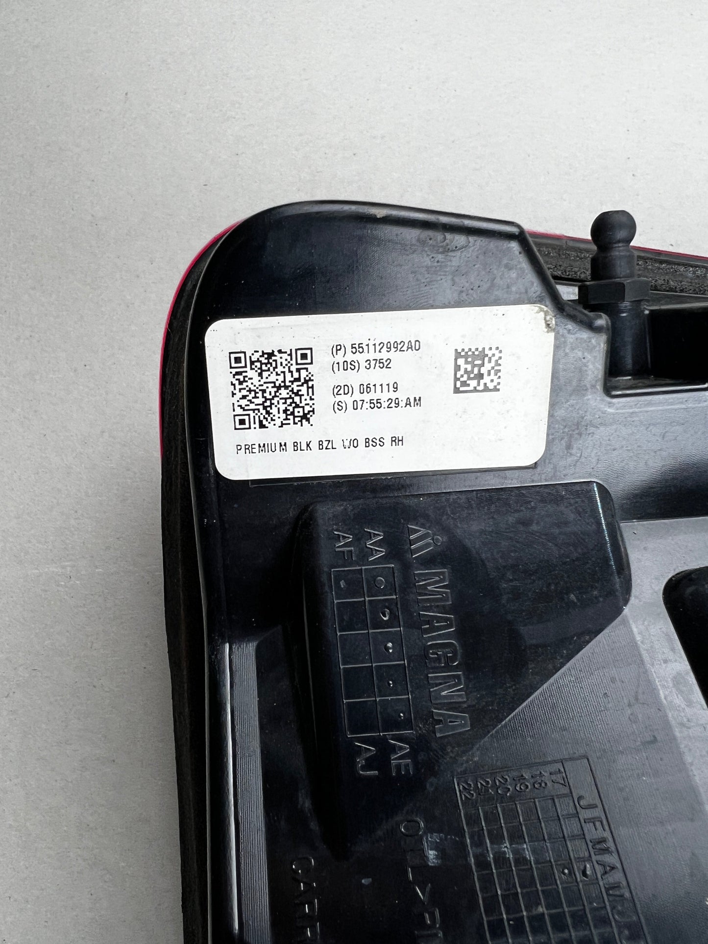 "Close-up of the manufacturer label on a RAM 1500 RH tail light, showing part number 55112992AD and Magna logo. Genuine Mopar part."