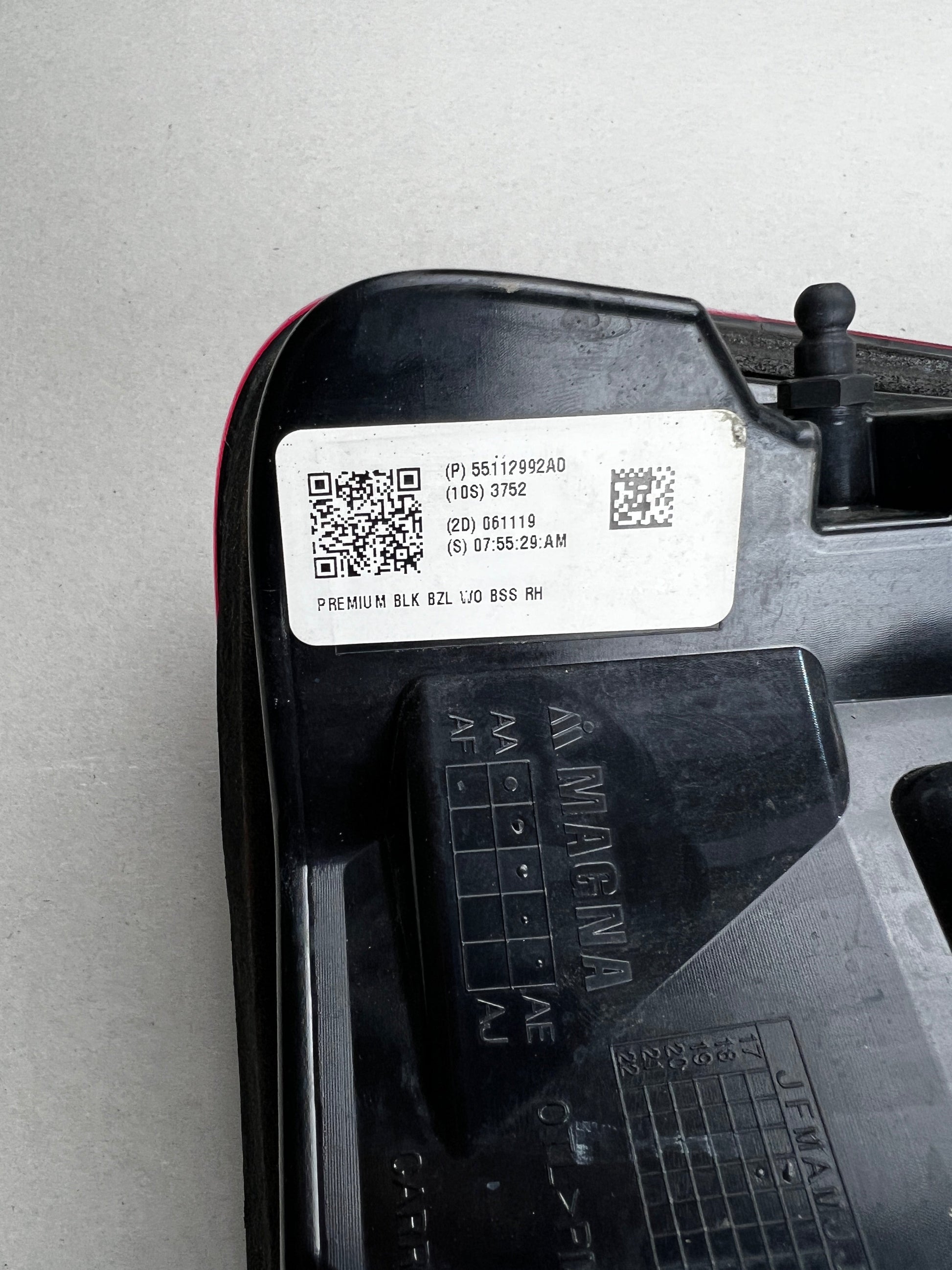 "Close-up of the manufacturer label on a RAM 1500 RH tail light, showing part number 55112992AD and Magna logo. Genuine Mopar part."